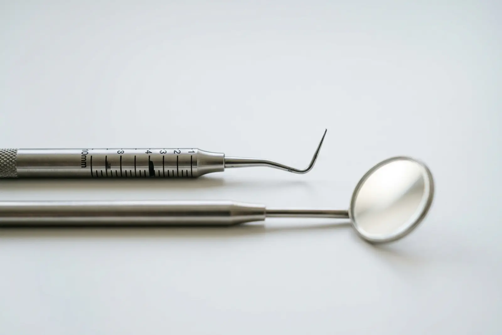 Sonda periodontal milimetrada junto a un espejo dental